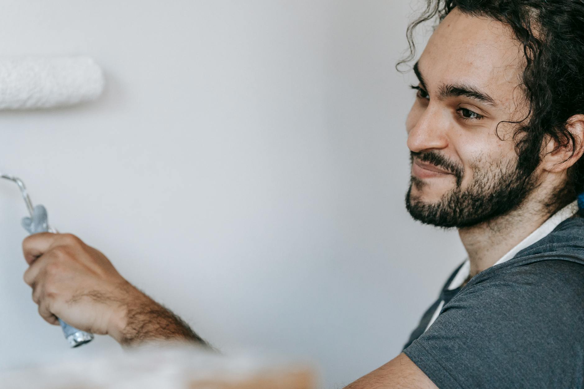 Happy man painting a wall at home, expressing joy and satisfaction.