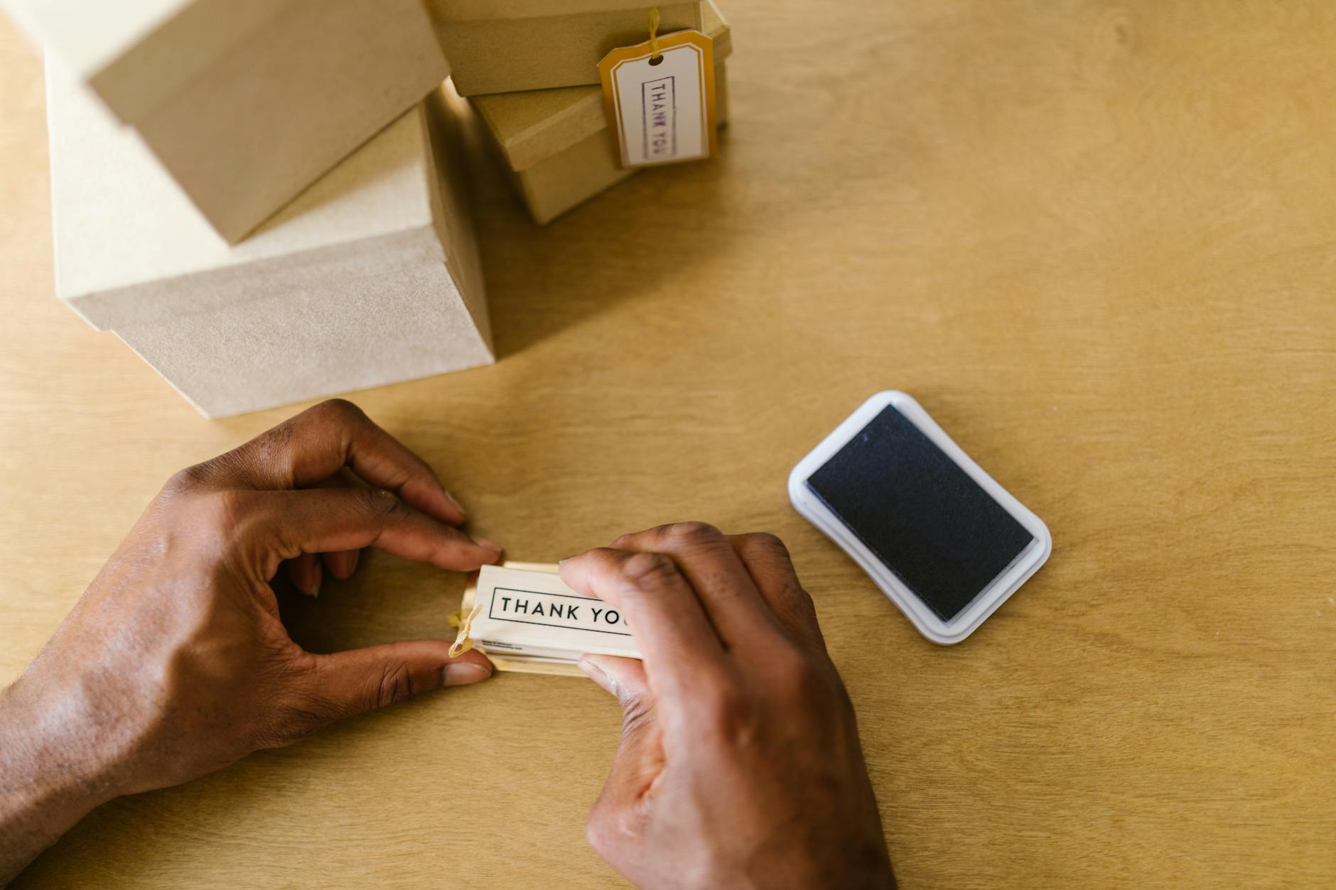 Hands of a small business owner sealing thank you cards with an ink pad.