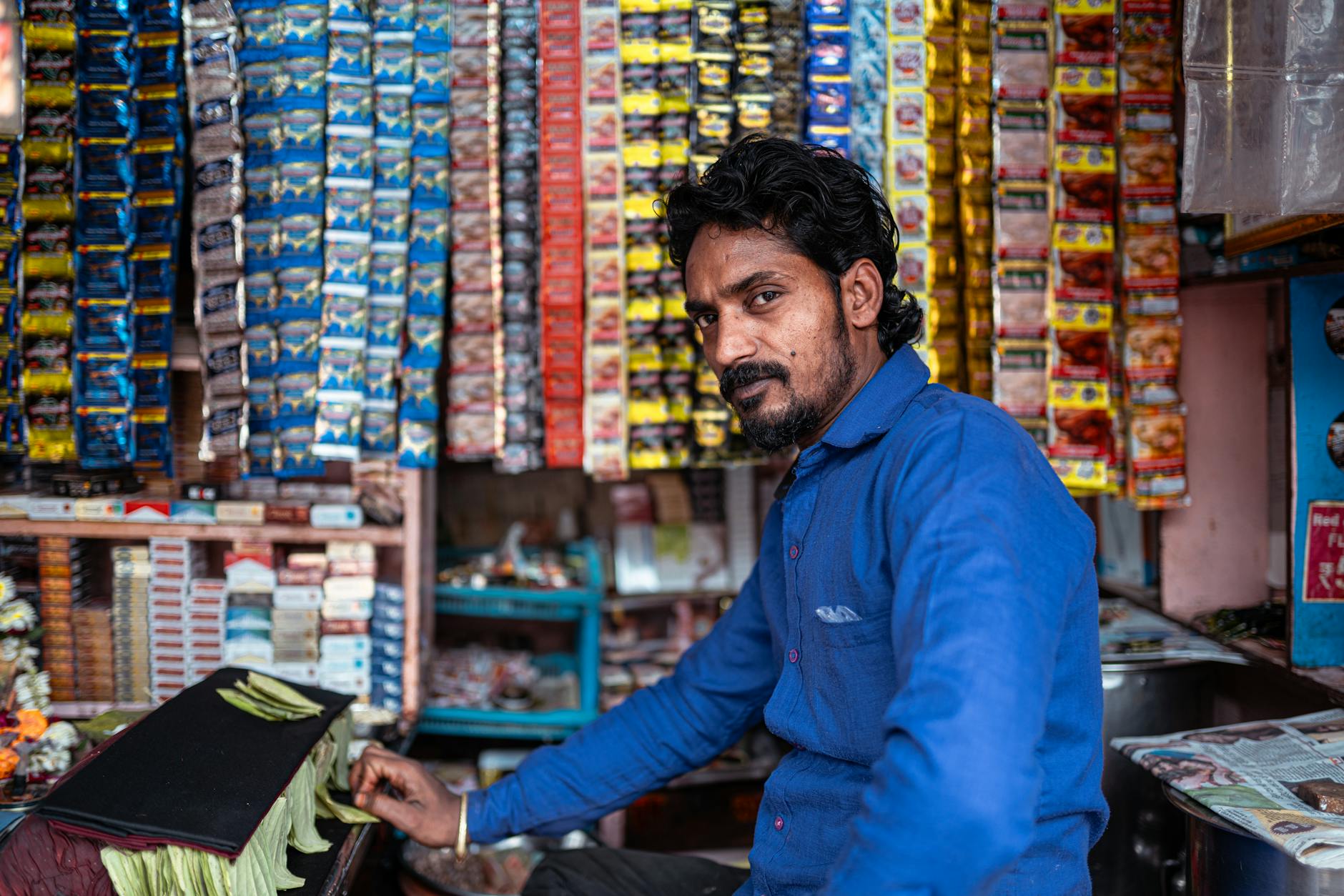 Portrait of a man working in a colorful tobacco shop in Varanasi, India.