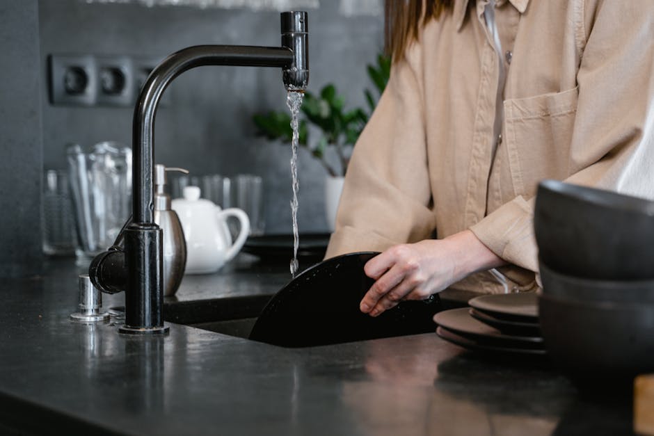 A woman pouring natural enzyme cleaning solution into a kitchen sink drain in a bright modern suburban kitchen