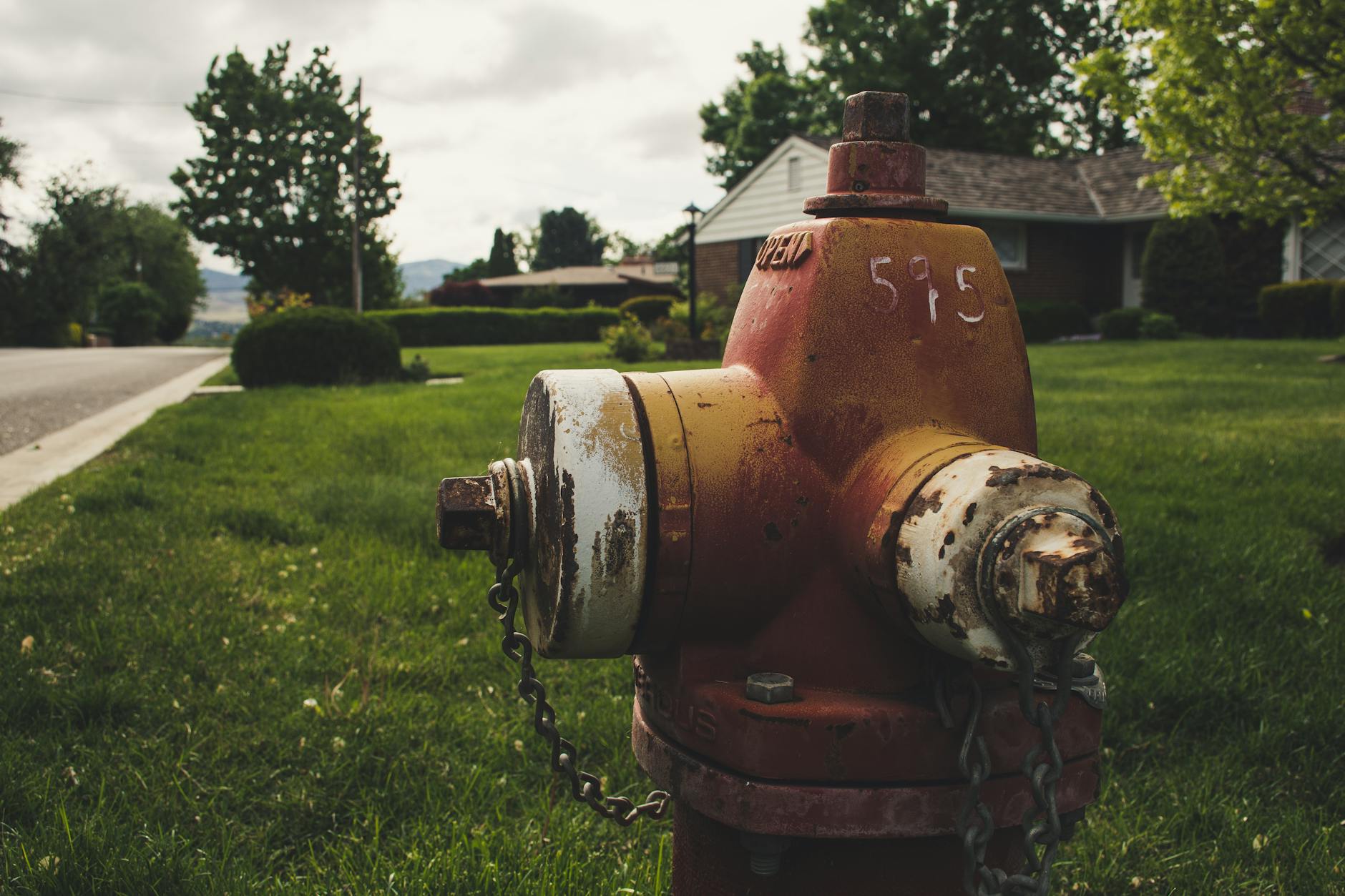 A weathered fire hydrant on a sunny day in a quiet suburban street.