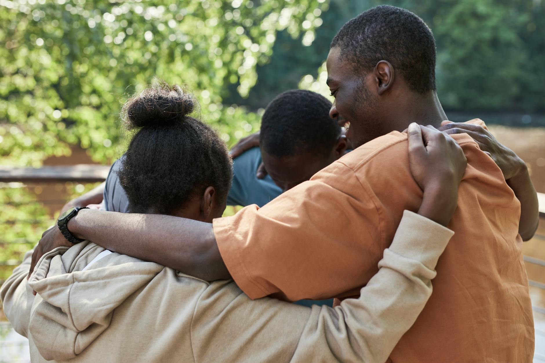 A group of people hugging outdoors, symbolizing friendship and unity.